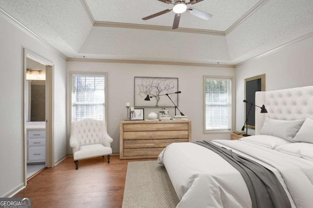 bedroom with wood finished floors, a raised ceiling, a textured ceiling, and ornamental molding