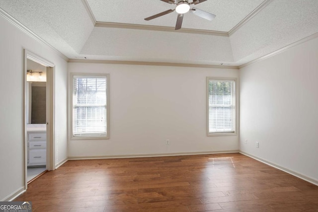 unfurnished bedroom featuring a textured ceiling, wood finished floors, a raised ceiling, and ornamental molding