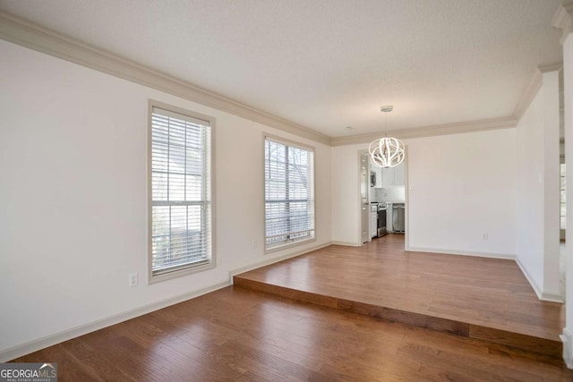 unfurnished dining area with crown molding, baseboards, light wood-style flooring, a notable chandelier, and a textured ceiling