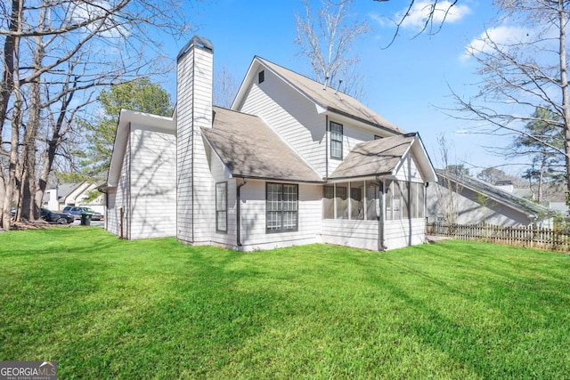 view of side of home with a yard, fence, a chimney, and a sunroom