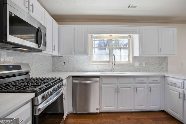 kitchen featuring a sink, appliances with stainless steel finishes, light countertops, and white cabinetry