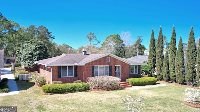 ranch-style house with brick siding, a chimney, and a front lawn