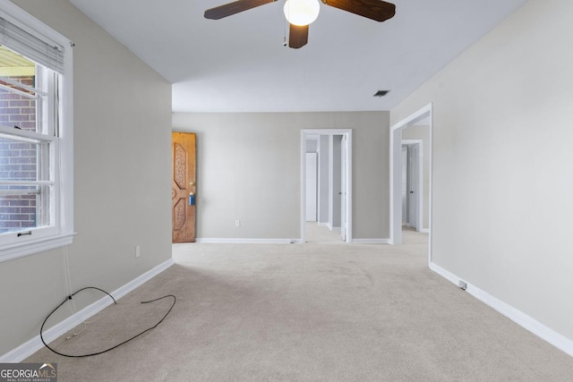 carpeted empty room with visible vents, baseboards, and ceiling fan