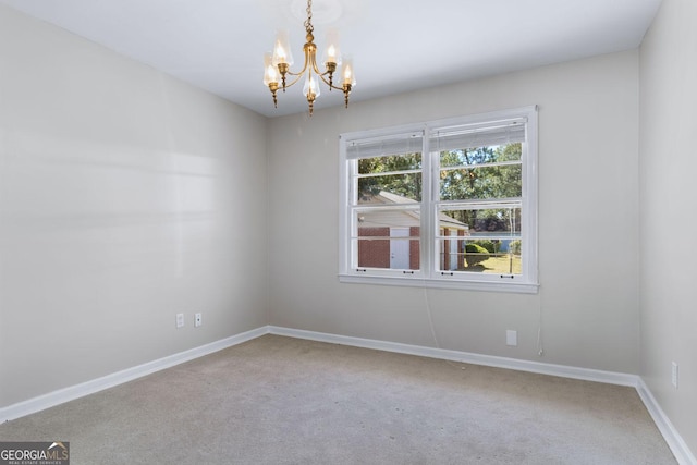 spare room with a notable chandelier, baseboards, and carpet