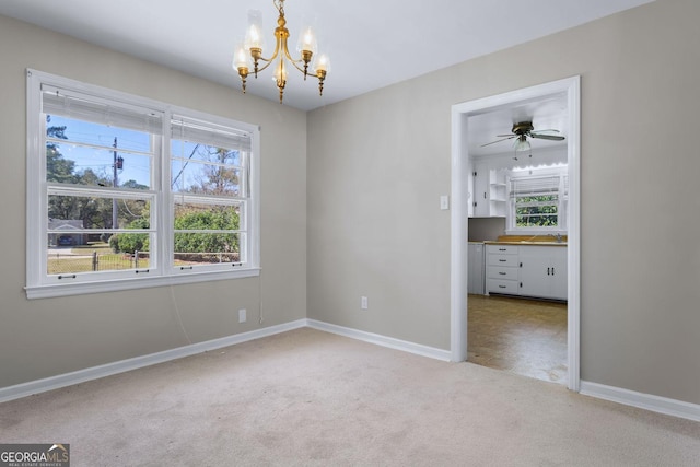 spare room with a notable chandelier, baseboards, carpet, and a sink