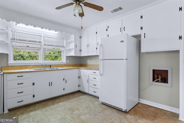 kitchen featuring a sink, light countertops, freestanding refrigerator, and open shelves