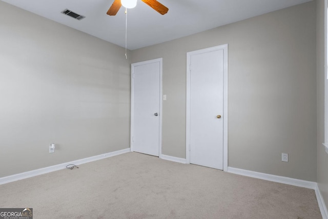 unfurnished bedroom featuring visible vents, light colored carpet, a ceiling fan, and baseboards