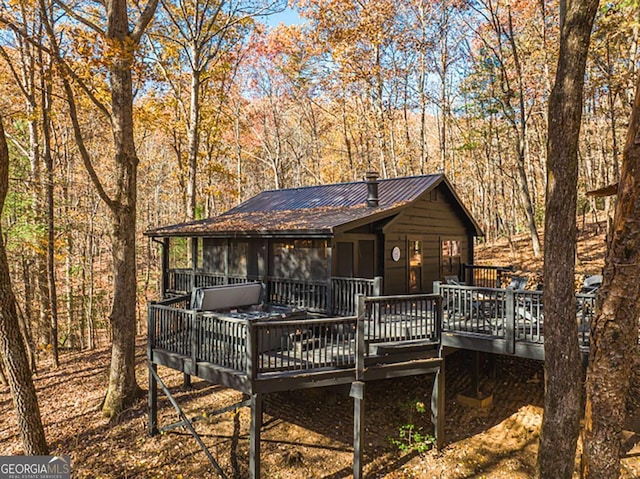 rear view of house with a forest view, metal roof, and a deck