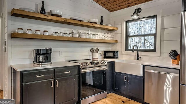 bar featuring wood ceiling, vaulted ceiling, light wood-style floors, stainless steel appliances, and a sink