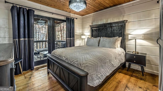 bedroom with hardwood / wood-style floors, an inviting chandelier, wooden ceiling, and access to outside