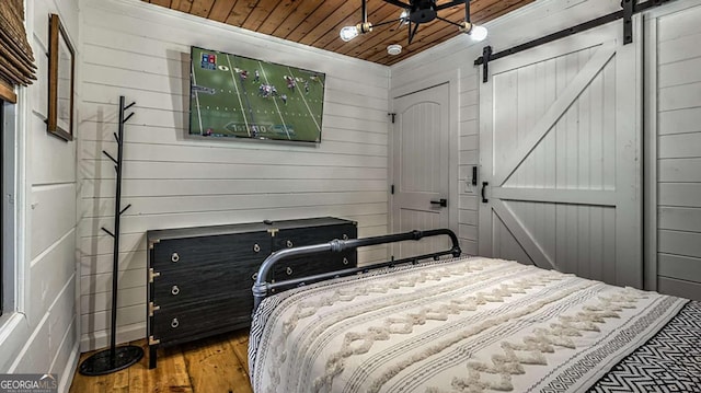 bedroom with wood ceiling, a barn door, and wood finished floors