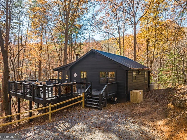 exterior space featuring a wooden deck, a view of trees, and metal roof