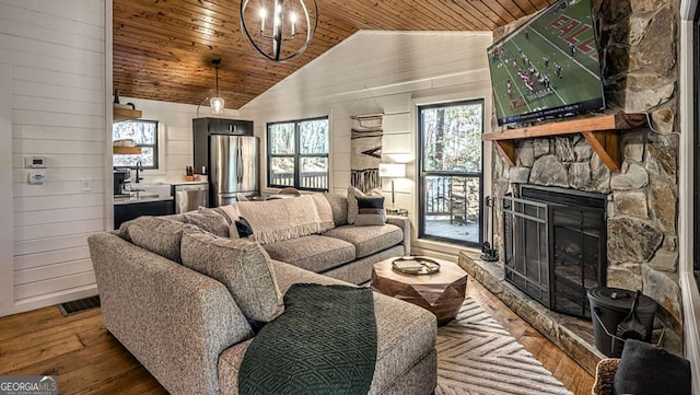 living area with vaulted ceiling, wood ceiling, a stone fireplace, and hardwood / wood-style flooring