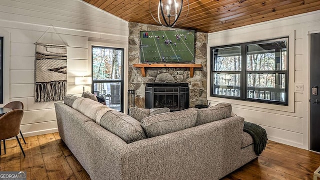 living room with wooden walls, lofted ceiling, a stone fireplace, wood-type flooring, and wooden ceiling