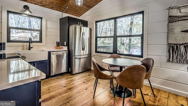 kitchen with lofted ceiling, a sink, light countertops, appliances with stainless steel finishes, and wooden ceiling