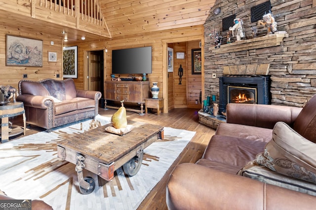 living area featuring hardwood / wood-style flooring, wooden walls, a fireplace, and high vaulted ceiling