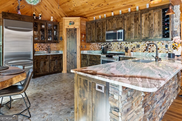 kitchen featuring wood ceiling, decorative backsplash, a peninsula, stainless steel appliances, and a sink