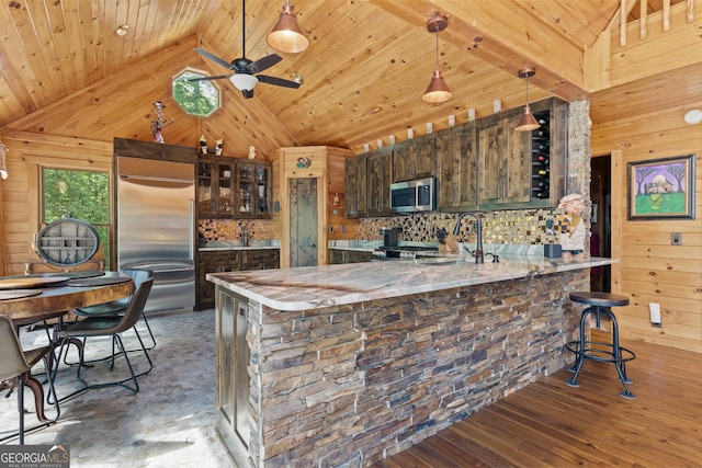 kitchen with wooden ceiling, wood walls, appliances with stainless steel finishes, and a sink