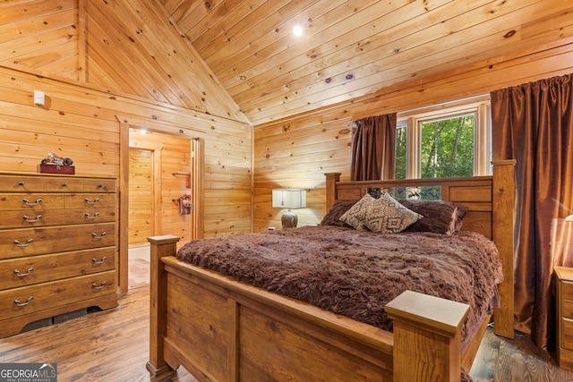 bedroom with wooden walls, wood ceiling, hardwood / wood-style floors, vaulted ceiling, and ensuite bath