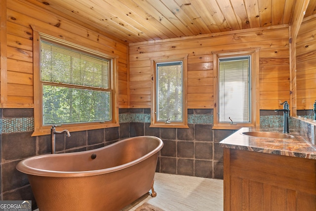 bathroom with vanity, wooden ceiling, a soaking tub, and tile walls