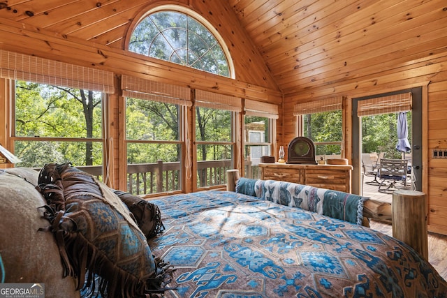 bedroom featuring multiple windows, wood walls, and access to outside