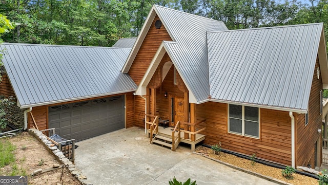 rustic home featuring concrete driveway, a garage, and metal roof