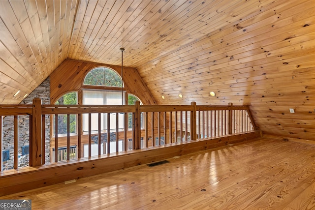 bonus room featuring wooden walls, wood finished floors, visible vents, vaulted ceiling, and wooden ceiling