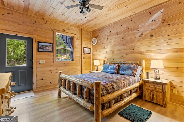 bedroom with light wood-type flooring, wooden walls, wooden ceiling, and a ceiling fan