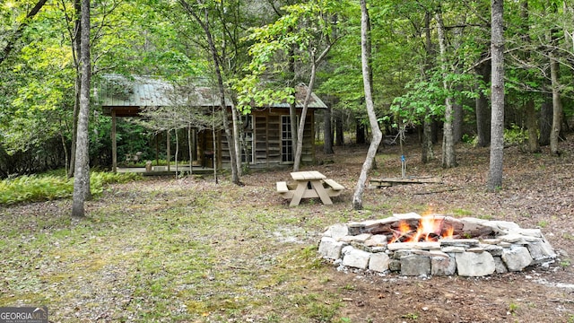 view of yard featuring a forest view and an outdoor fire pit