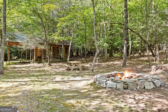 view of yard featuring a wooded view and an outdoor fire pit