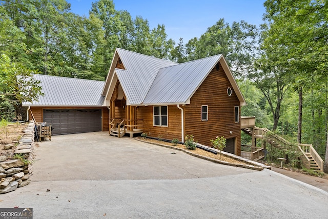 view of front of house featuring a garage, metal roof, concrete driveway, and stairway