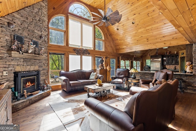 living area with a stone fireplace, a healthy amount of sunlight, and hardwood / wood-style floors