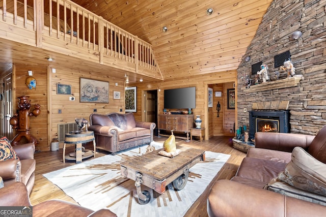 living area featuring wooden walls, wood ceiling, hardwood / wood-style floors, and a fireplace