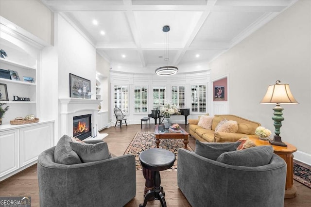 living area with beamed ceiling, built in features, wood finished floors, a glass covered fireplace, and coffered ceiling