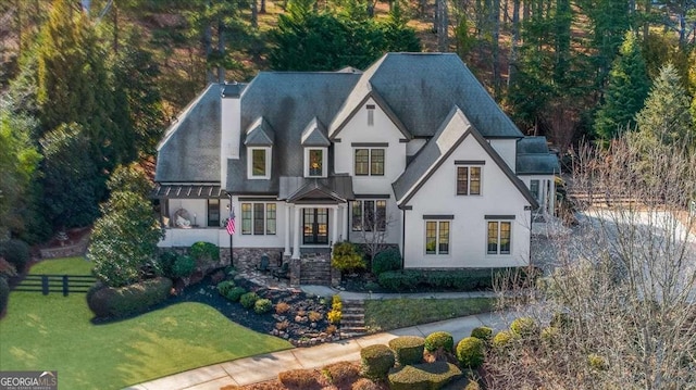 view of front of home featuring a front lawn, fence, a chimney, and stucco siding