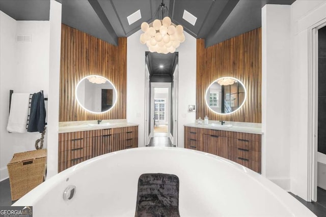 bathroom featuring a soaking tub, vaulted ceiling with skylight, visible vents, and a sink