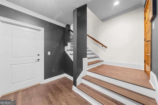 foyer entrance with stairs, wood finished floors, baseboards, and ornamental molding