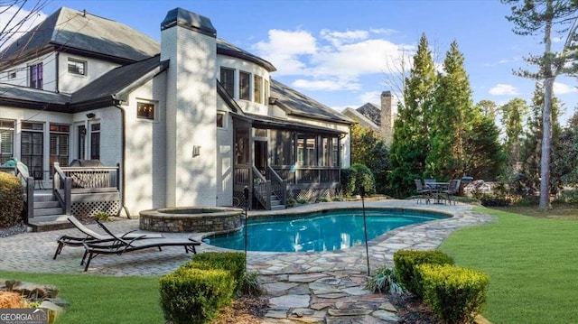 view of pool featuring a deck, a pool with connected hot tub, a yard, a sunroom, and a patio area