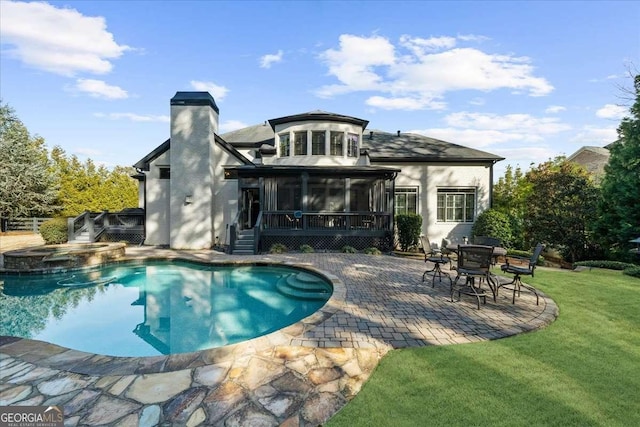 rear view of property featuring a patio, a sunroom, an outdoor pool, an in ground hot tub, and a chimney