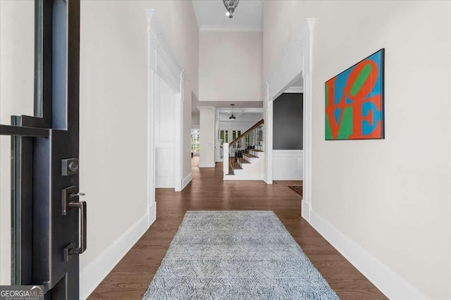 foyer with stairs, crown molding, and dark wood-style floors