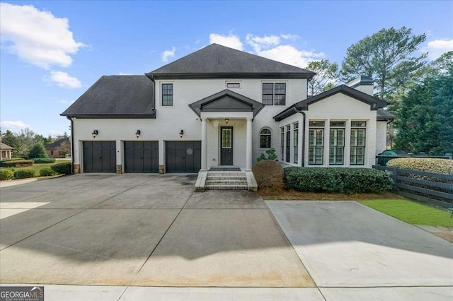 view of front of house featuring a shingled roof, concrete driveway, a garage, and fence