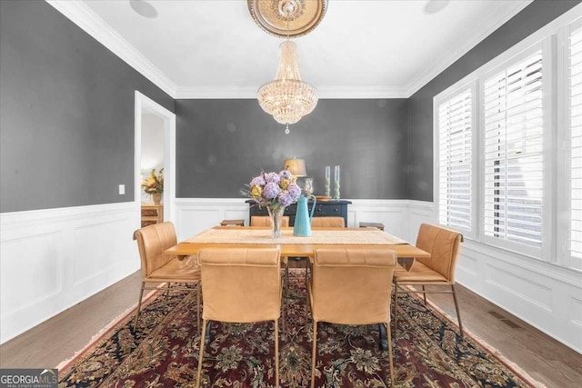 dining area featuring a wainscoted wall, a healthy amount of sunlight, crown molding, and wood finished floors