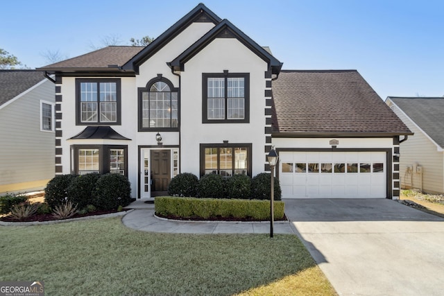 view of front facade with roof with shingles, driveway, an attached garage, stucco siding, and a front lawn