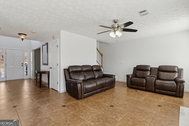 living room featuring visible vents, baseboards, stairs, light tile patterned flooring, and a textured ceiling