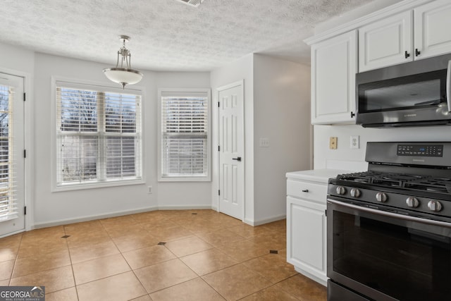 kitchen featuring light tile patterned floors, appliances with stainless steel finishes, light countertops, and white cabinetry