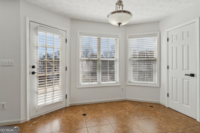 entryway with tile patterned floors, baseboards, and a textured ceiling