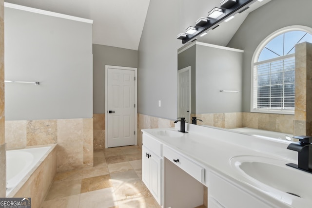 full bath with lofted ceiling, a garden tub, tile walls, and a sink