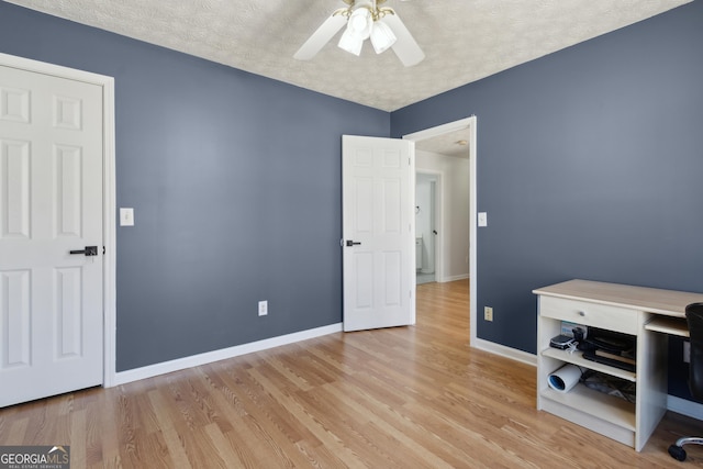 bedroom with light wood-style flooring, a textured ceiling, baseboards, and a ceiling fan