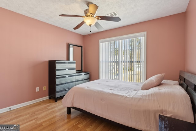 bedroom featuring visible vents, baseboards, a textured ceiling, and light wood finished floors