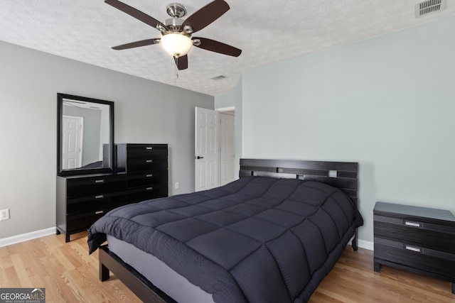 bedroom with visible vents, baseboards, light wood-style floors, and a textured ceiling